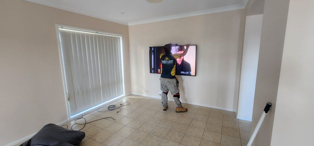 Ranjit mounting a TV on a living room wall